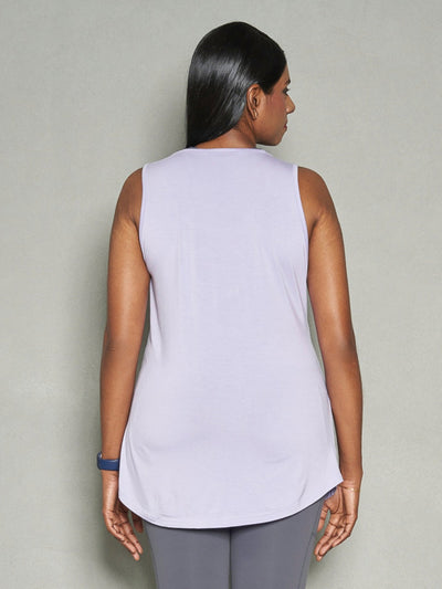 A shot of a woman from the back wearing purple women's tank top and grey leggings.