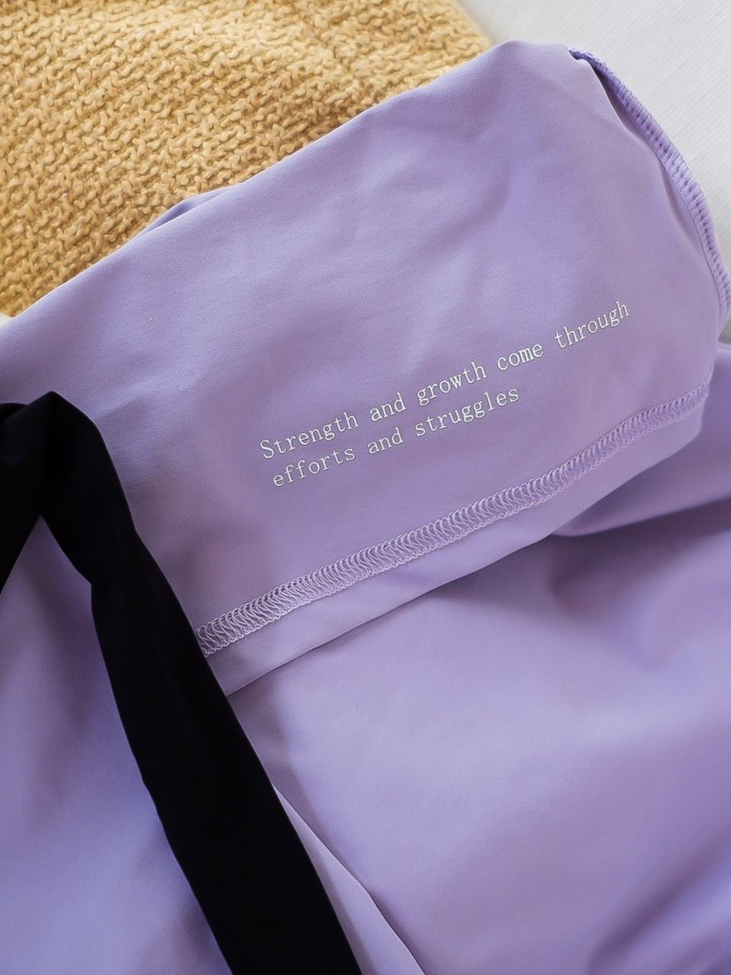 "Strength and growth come through efforts and struggles" written on the inside of purple women's workout top.