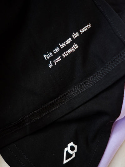 "Pain can become the source of your strength" is written on the inside of a women's workout top.