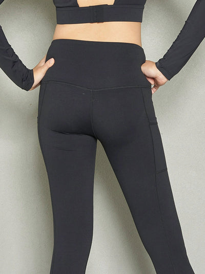 A shot of a woman's backside wearing black leggings with both hands on her hips.