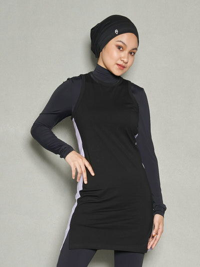 A front shot of a woman tilting her head facing forward and her right hand on her hips. She is wearing ZHOORA Sports Hijab, Long Sleeve Sports Bra, Women's Workout Top Dress and Black Leggings.