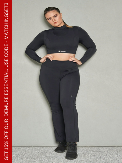 A shot of a woman wearing a matching set of black bootleg pants and long sleeves sports bra